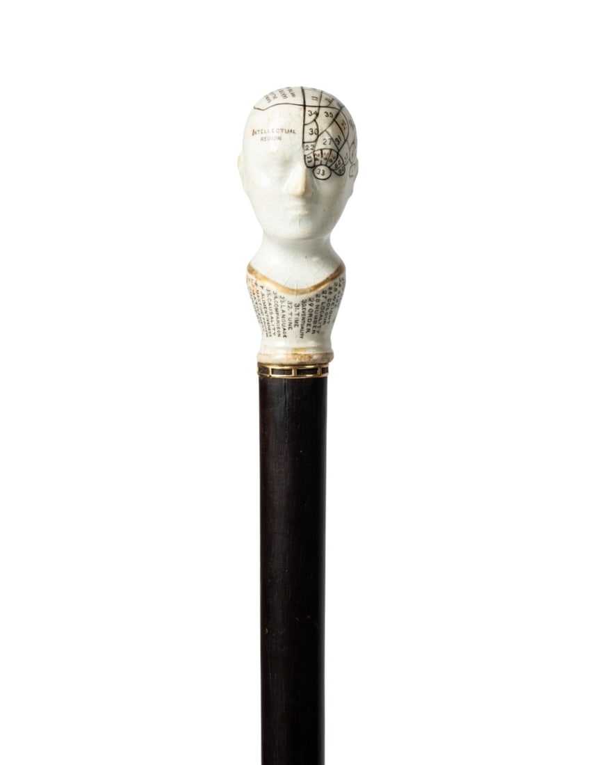 19TH C. GERMAN PORCELAIN PHRENOLOGY HEAD CANE: German, circa 1860. Walking cane with porcelain phrenology head handle, with a white crackle glaze, black lettering, and gold highlighting, gold wire collar leads to a shaft of Macassar ebony wood, an