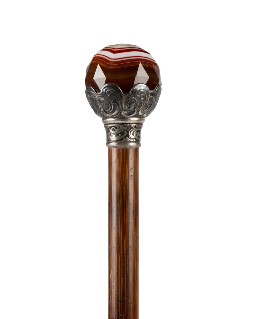 TIFFANY & CO POLISHED AGATE DRESS CANE: American, circa 1900. Tiffany & Co (American, founded 1837). Walking cane with polished, fully faceted and rose cut agate stone set in sterling silver cup mount decorated with C-scrolls, collar marked
