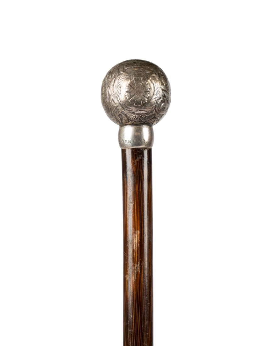 TIFFANY & CO STERLING SILVER BALL HANDLE CANE: American, circa 1920. Tiffany & Company (American, founded 1837). Sterling silver topped walking cane with an elaborately decorated silver ball handle showing flower blossoms, horns of plenty, and a f