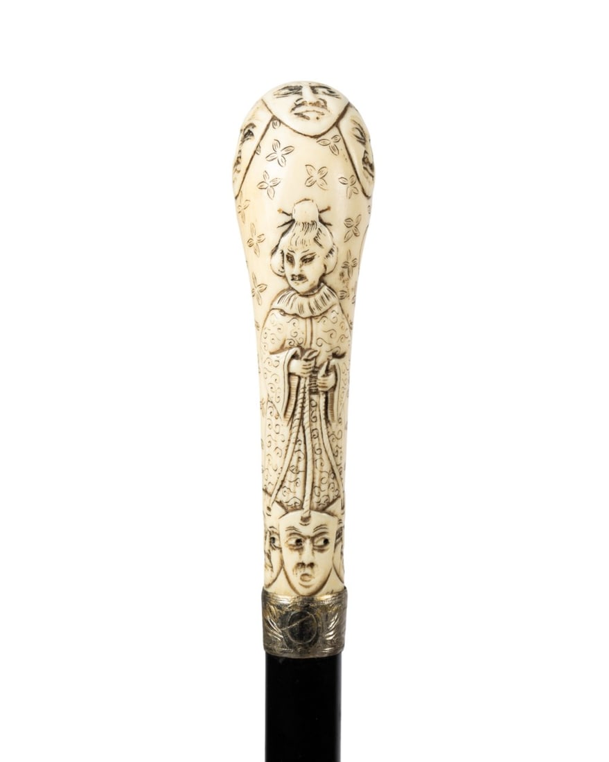 19TH C. JAPANESE FIGURAL WALKING CANE: Japanese, circa 1890. Walking cane with carved handle depicting Japanese figure in ceremonial robes holding cords with three masks at base and additional carving at top, silver collar, ebonized hardwo