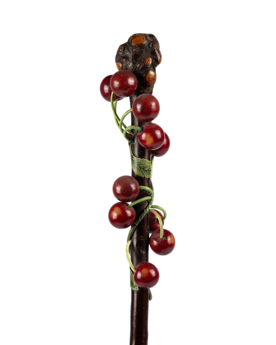 ENGLISH CARVED CHERRY WALKING CANE, C. 1879: English, circa 1879. Walking cane with handle of ten carved and red-dyed bone cherries on twisting stems with applied metal leaves, cherry wood top and shaft, and brass ferrule. Approximate measuremen