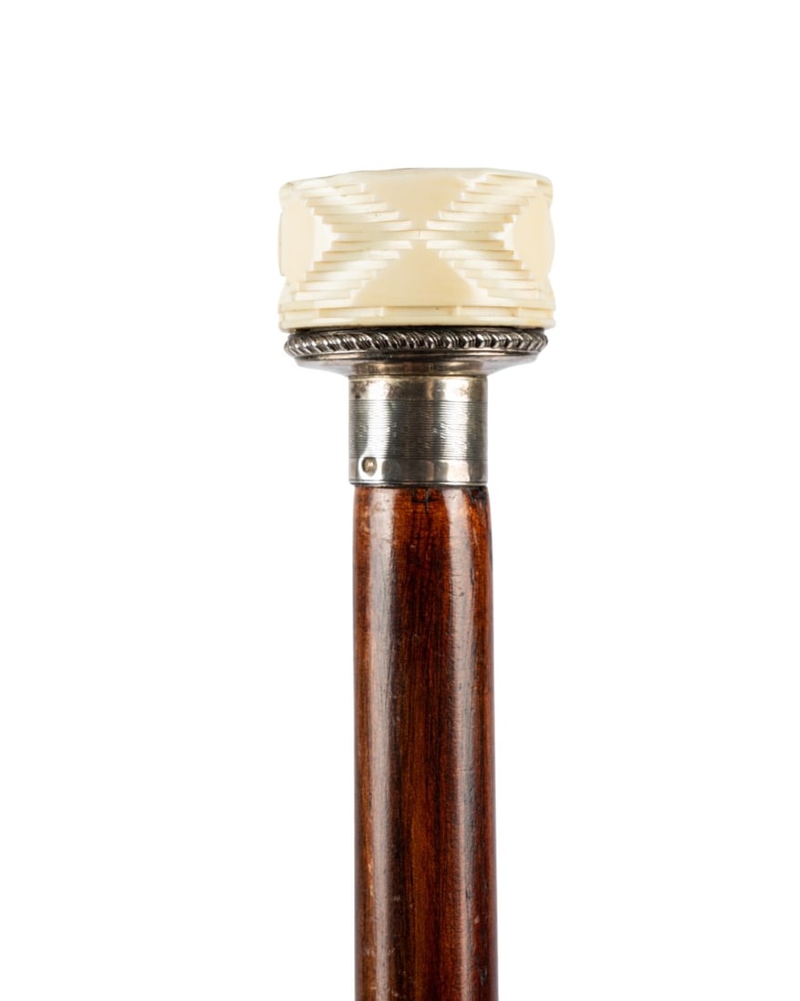 WRITER'S GADGET CANE, C. 1900: Continental, circa 1900. Walking cane with a finely carved handle, a silver collar, a stained hardwood shaft, and a metal ferrule, the handle unscrewing to reveal three writing tools. Approximate