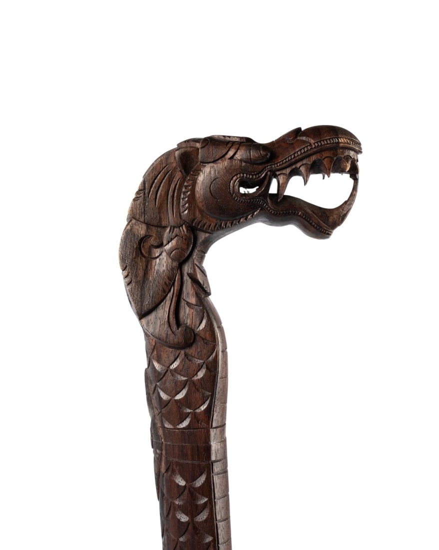 CHINESE DRAGON HANDLED CANE, C. 1910: Chinese, circa 1910. Walking cane with an intricately carved wood handle depicting a snarling Asian dragon with bared teeth, the shaft continuing as the dragon?s body and terminating in a carved wood