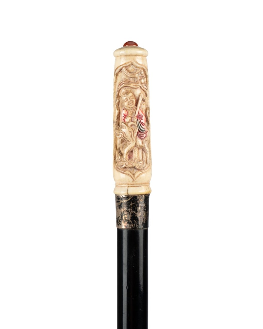 19TH C. CHINESE FIGURAL WALKING CANE: Chinese, circa 1890. Walking cane with long carved handle depicting a figure riding an elephant and holding a stave, partly colored, metal collar, ebonized hardwood shaft, and horn ferrule. 