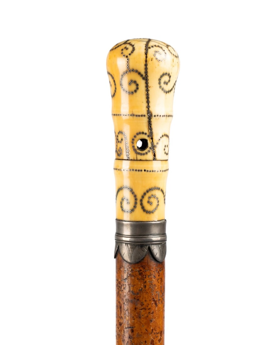 FRENCH CARVED PIQUE CANE, C. 1680: French, circa 1680. Pique walking cane with large carved bone handle decorated with silver pique scrolls and loops, silver collar, honey-toned Malacca wood shaft, and original brass ferrule. Approxima