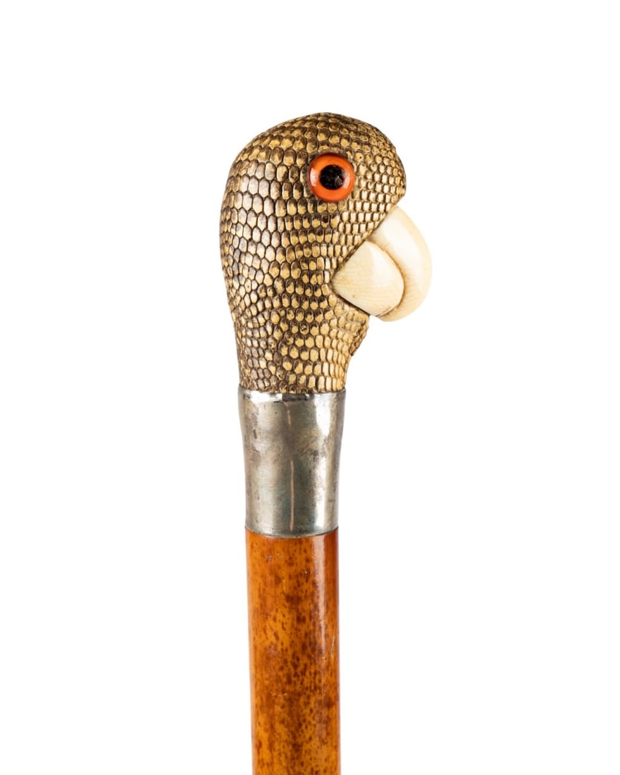 19TH C. PARROT HANDLE WALKING CANE: Continental, circa 1890. Walking cane with parrot head handle covered in shark or lizard skin with glass eyes and carved bone beak, silver collar, light-colored grained Malacca shaft, and bone ferrule