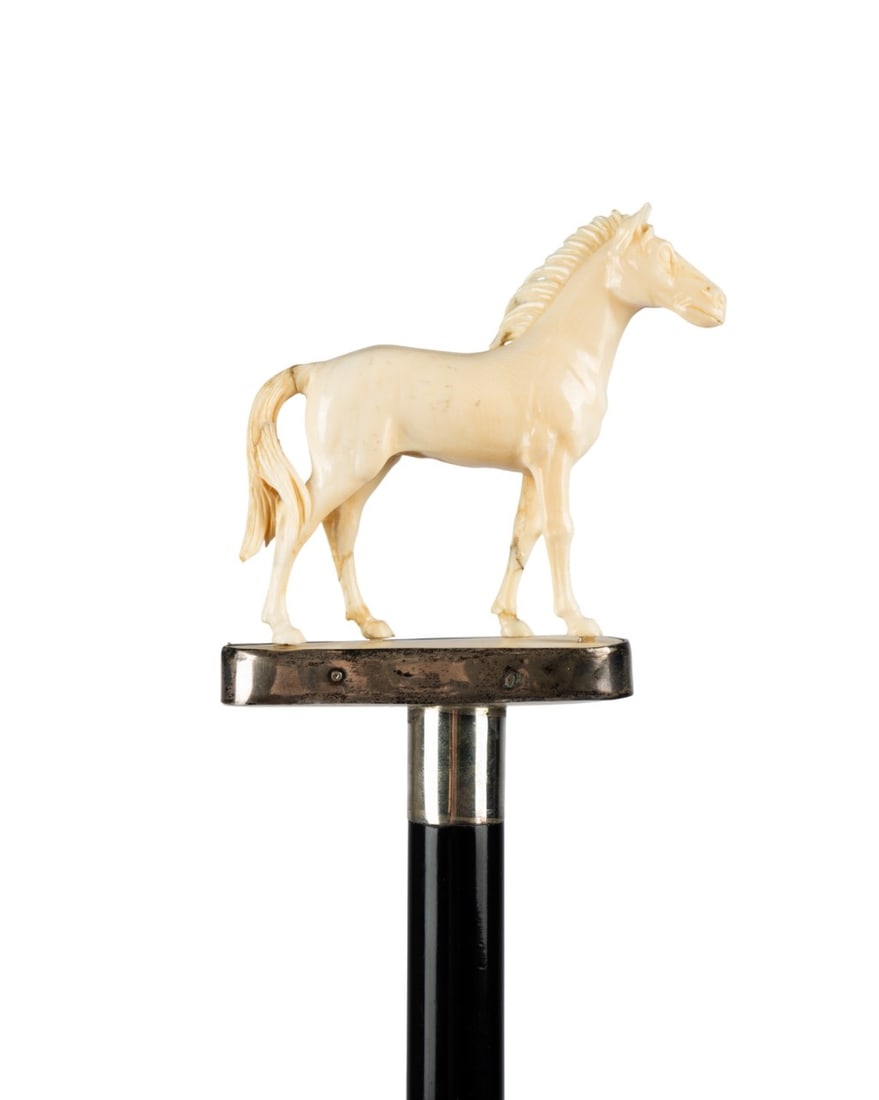 19TH C. ENGLISH HORSE WALKING CANE: English, circa 1890. Walking cane with handle depicting full standing horse with bushy mane and tail on carved base surrounded by silver, with silver collar, ebony shaft, and horn ferrule. Approximate