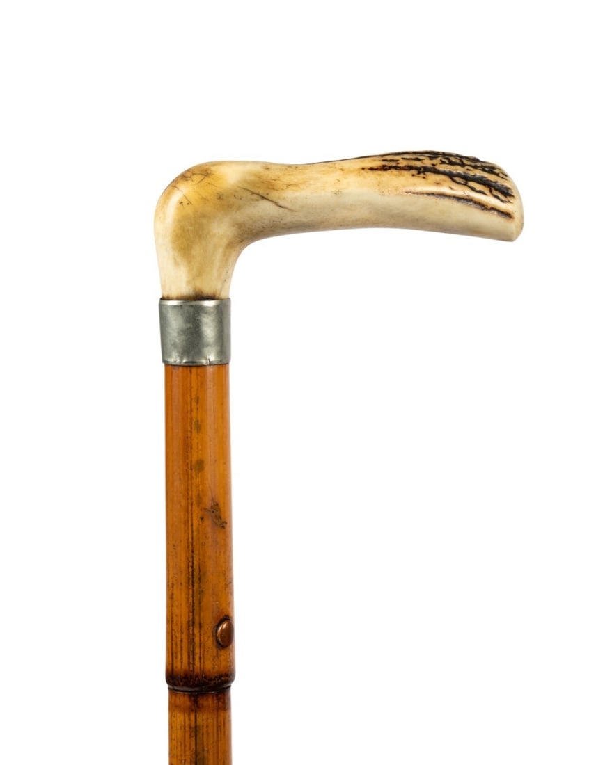 19TH C. STAG HORN & MALACCA WOOD SWORD CANE: Continental, circa 1835. Walking cane with L-shaped stag horn handle supported by plain silver collar, Malacca wood shaft with metal ferrule, wooden button six inches below collar engaging tongue latc