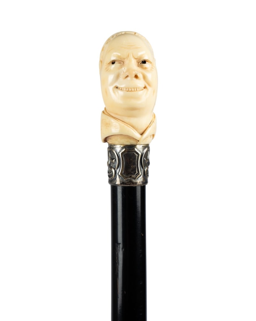 FRENCH MONK HEAD HANDLE WALKING CANE, C. 1870: French, circa 1870. Walking cane with carved Roman Catholic Cardinal bust handle, with a smirking expression and dark-centered eyes, signed "Gagnepoin" at the back, with silver collar, ebonized hardwo