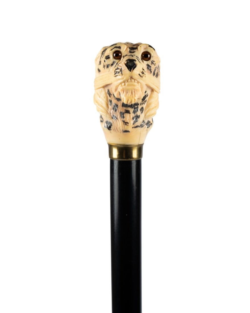 19TH C. LYNX HEAD HANDLE WALKING CANE: Continental, circa 1890. Walking cane with carved lynx handle, with inset glass eyes, black markings, finely detailed whiskers, gilt collar, ebonized hardwood shaft, and horn ferrule. Approximate meas