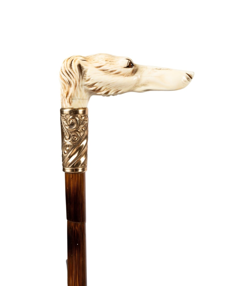 ENGLISH BORZOI WALKING CANE, C. 1890: English, circa 1890. Walking cane with carved L-shaped handle depicting long nosed Borzoi Russian wolfhound with glass eyes and furry jowls, gold-filled collar, stepped partridge wood shaft, and