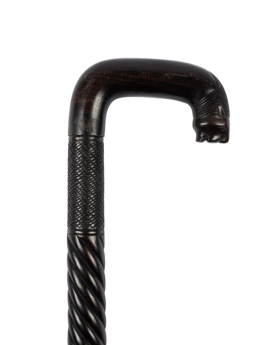 AFRICAN CARVED LION WALKING CANE, C. 1930: African, circa 1930. Walking cane with crook handle, with stylized lion carved on top with brushed back mane and face at end, shaft with repeating crosshatch and barley twist patterns, plain sections