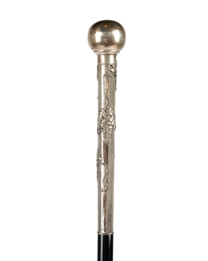 JAPANESE SILVER WALKING CANE, C. 1900: Japanese, circa 1900. Walking cane with silver ball handle extending down shaft decorated in relief with floral and botanical motifs, Japanese mark at base of handle, with ebonized hardwood shaft term