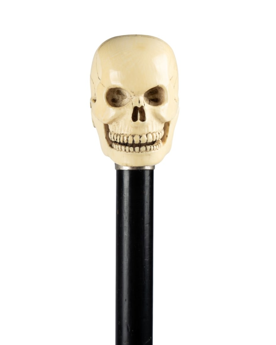 19TH C. ENGLISH SKULL WALKING CANE: English, circa 1890. Walking cane with carved bone skull handle with full set of teeth and delineated skull plates, articulated jaw, silver collar with appropriate marks, ebonized hardwood shaft, and