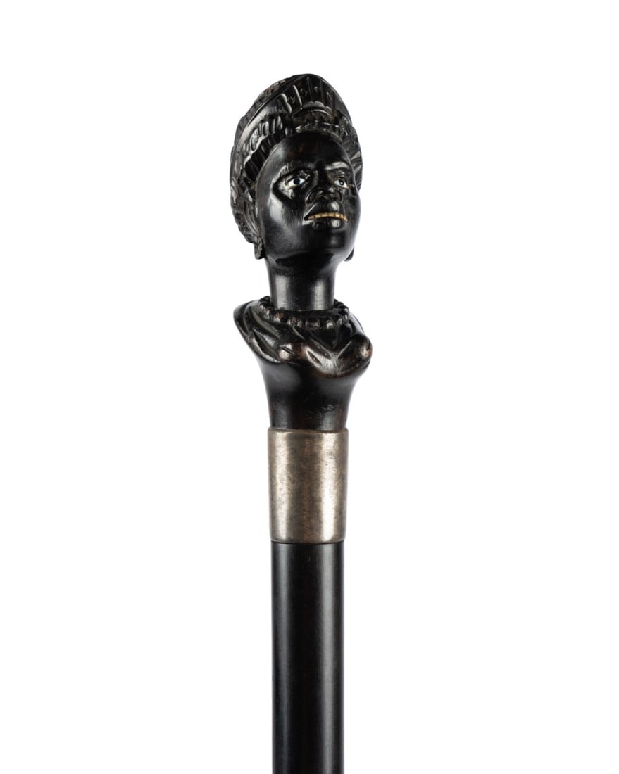 19TH C. AMERICAN FEMALE BUST WALKING CANE: American, circa 1880. Walking cane with carved ebony bust handle of a woman, metal collar, ebony shaft, and horn ferrule. Approximate measurements: length: 38.5"
