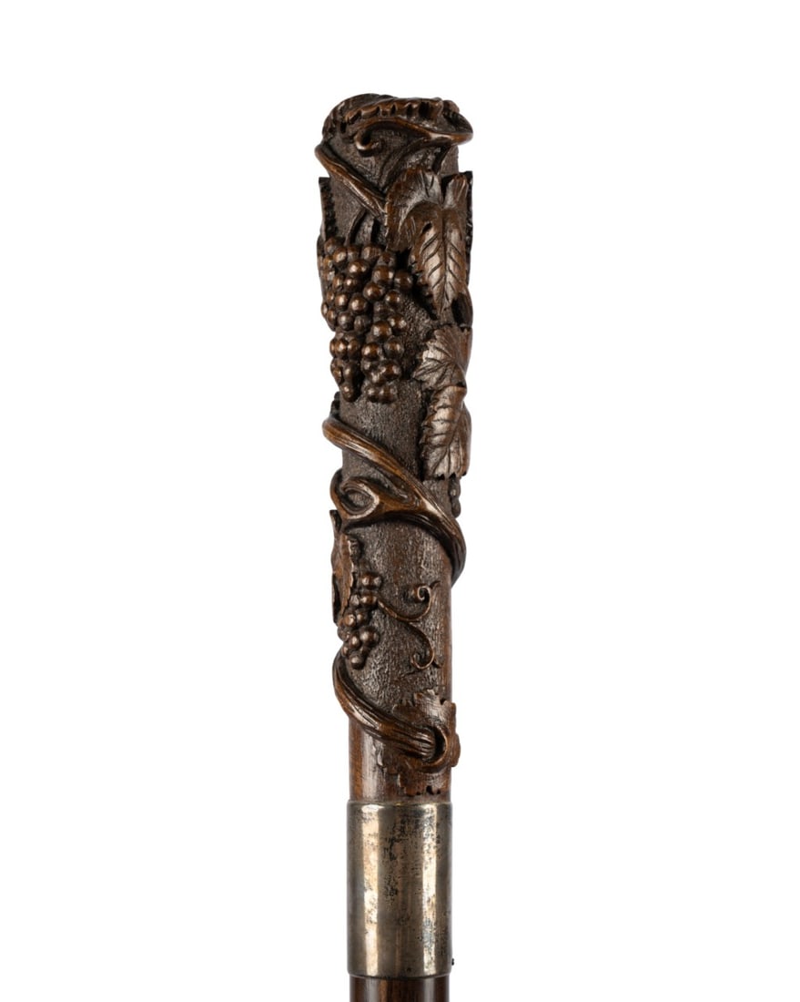 ENGLISH CARVED VINE RELIEF WALKING CANE: English, circa 1970. Walking cane with finely carved fruitwood handle of grapes and vines terminating at silver collar, with fruitwood shaft and bone ferrule. Approximate measurements: handle: