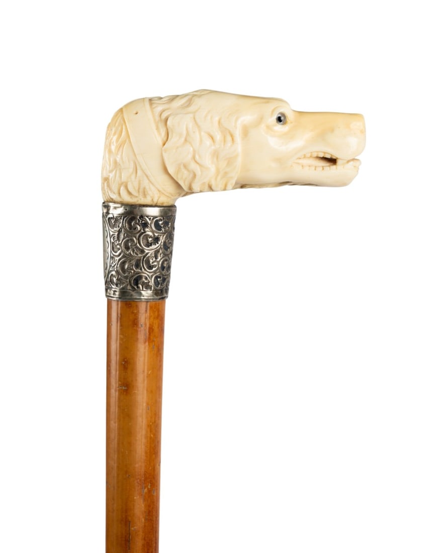 19TH C. ENGLISH DOG HEAD WALKING CANE: English, circa 1880. Walking cane with carved dog head handle with glass eyes and carved collar, highly decorated silver collar with blank engraved cartouche, Malacca shaft, and brass ferrule. Approxi