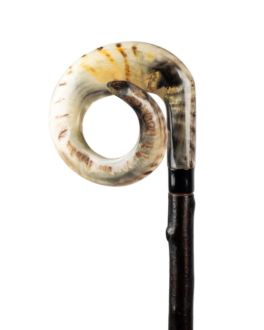 ENGLISH RAM HORN WALKING CANE, C. 1940: English, circa 1940. Walking cane with large curved ram horn handle on black bone collar engraved "No. 1021", oak shaft with full bark, and dark horn ferrule. Approximate measurements: handle: 6" tall