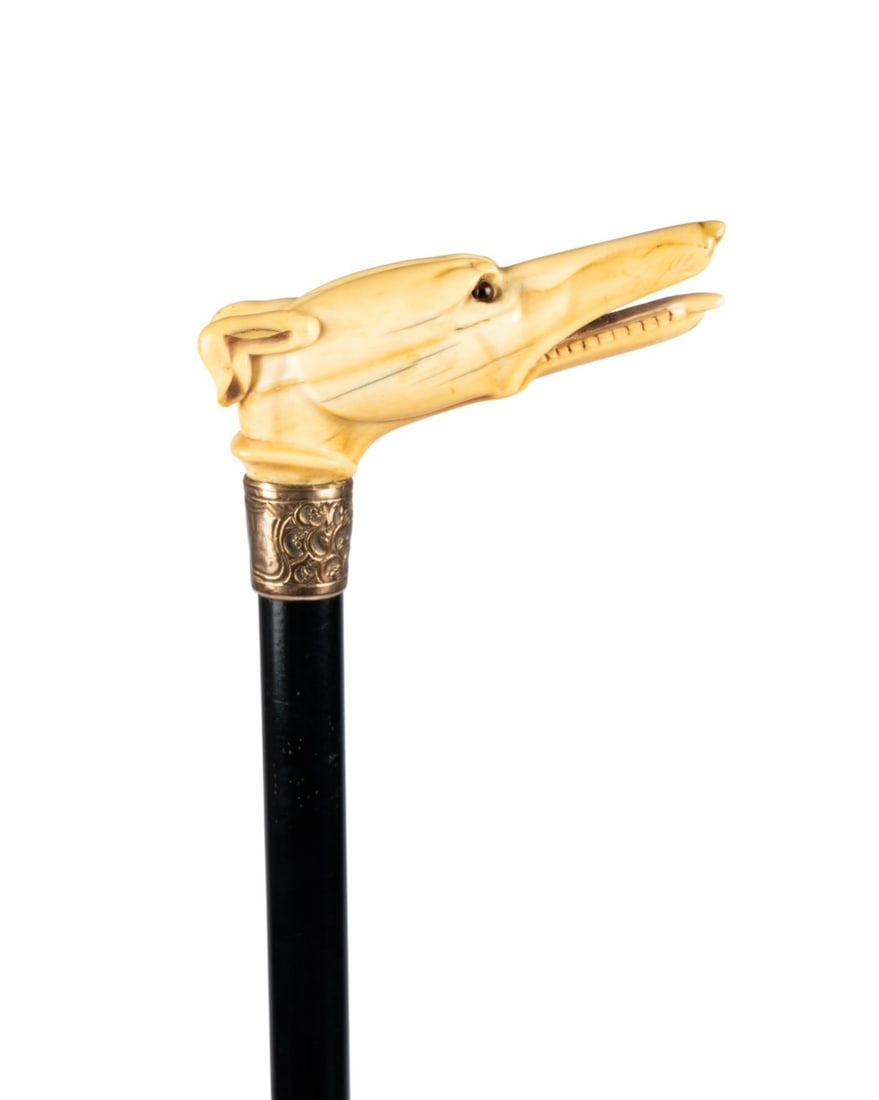 ENGLISH GREYHOUND WALKING CANE, C. 1870: English, circa 1870. Walking cane with carved bone greyhound head handle supported by etched metal collar, ebonized rosewood shaft, and horn ferrule. Approximate measurements: handle: 4.25"; length: 3