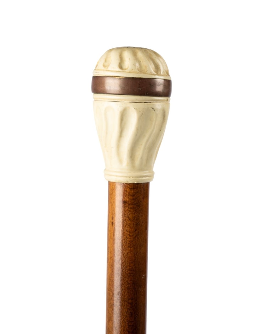 COMPASS & SUNDIAL GADGET WALKING CANE: Continental, circa 1982. Modern cane with carved bone handle with swirl design and scrimshaw sun at top, brass disk at handle top unscrewing to reveal built-in compass and sundial, stained birch wood
