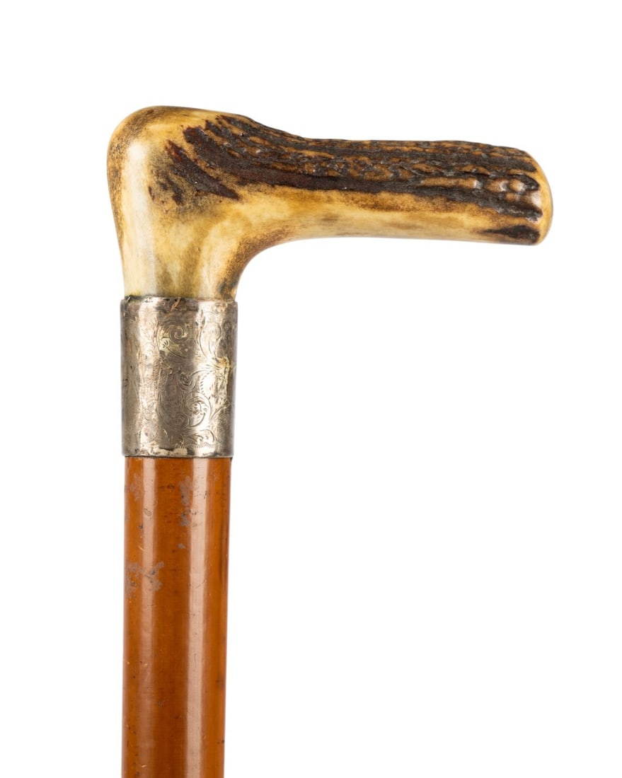 ENGLISH UTENSIL GADGET CANE, C. 1880: English, circa 1880. Walking cane with carved bone handle imitating stag horn, engraved silver collar with CHC monogram, stained maple shaft, and metal ferrule. Approximate measurements: length: