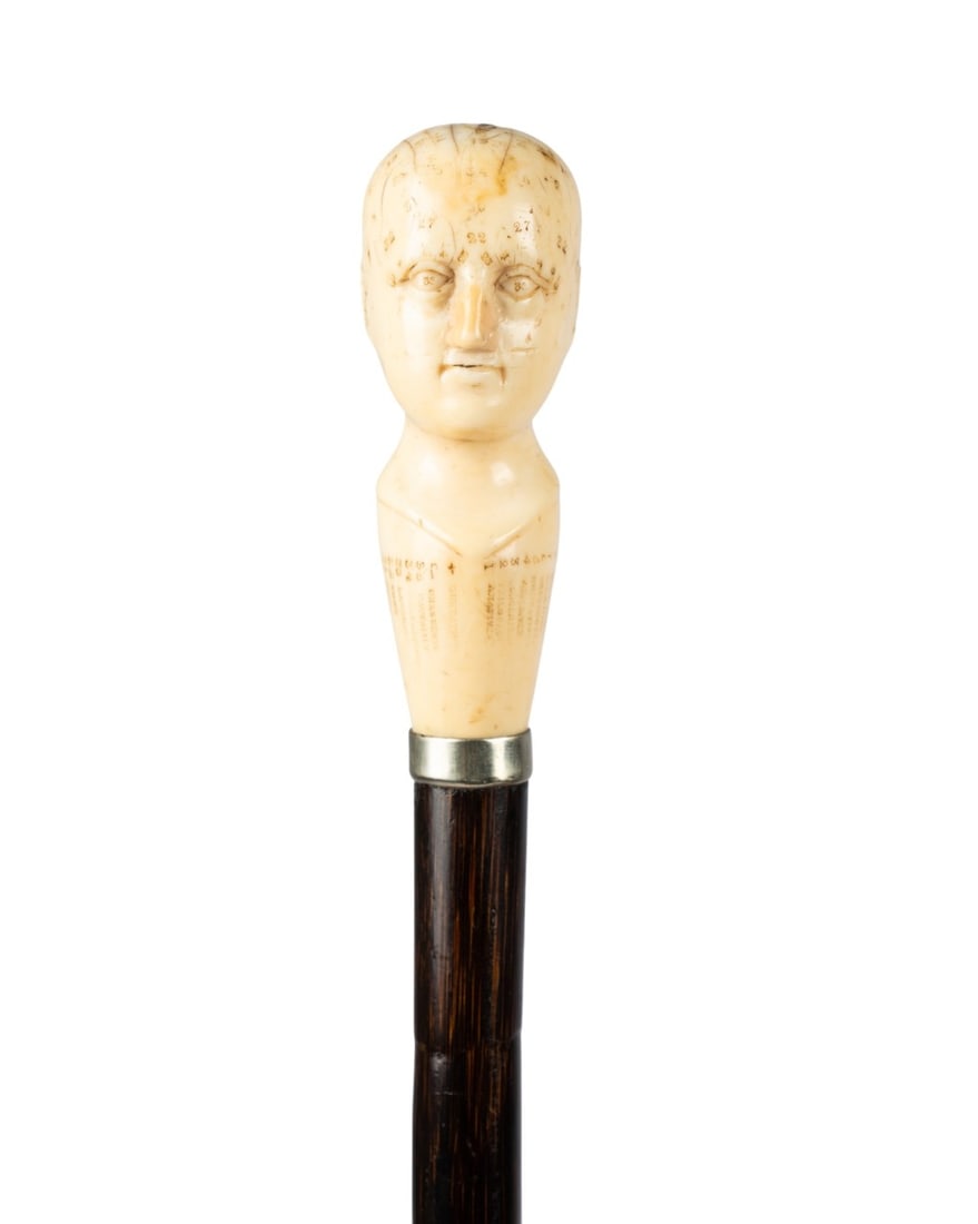 19TH C. ENGLISH PHRENOLOGY WALKING CANE: English, circa 1860. Walking cane with carved bone phrenology head handle numbered with legend around base, mounted on slim silver collar, partridgewood shaft, and brass ferrule. Approximate measureme