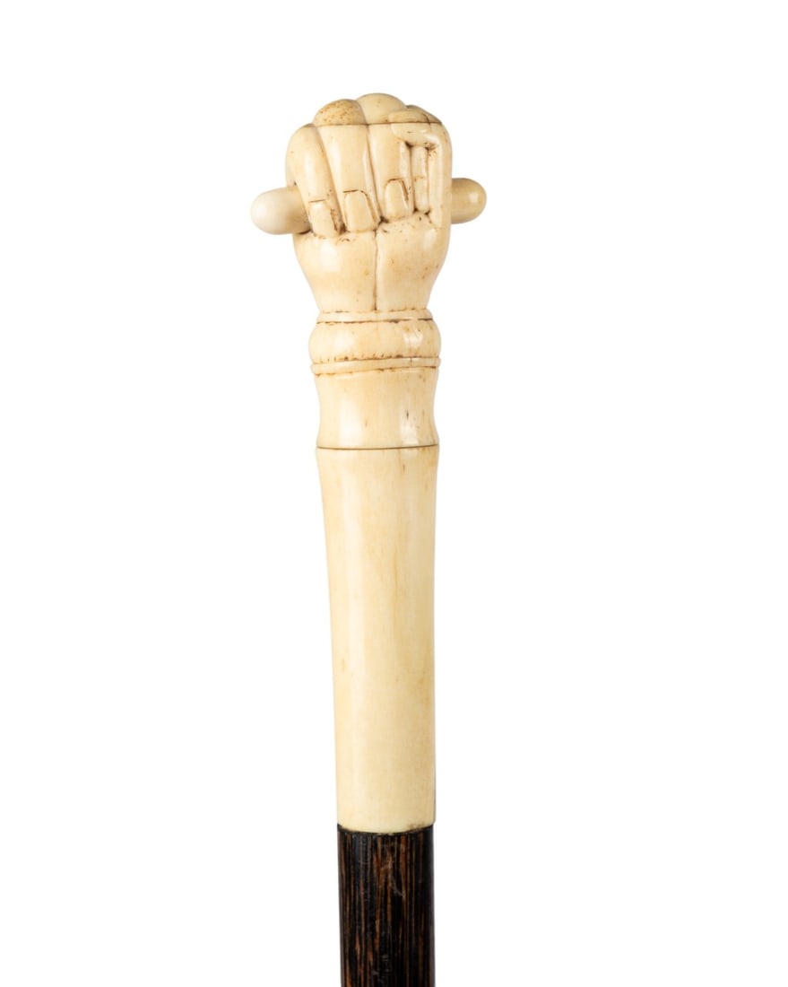 CLENCHED FIST CARVED HANDLE WALKING CANE, C. 1870: Continental, circa 1870. Walking cane with handle of three white bone pieces carved as clenched fist holding short baton, dark zebra wood shaft, and metal ferrule. Approximate measurements: length: 37