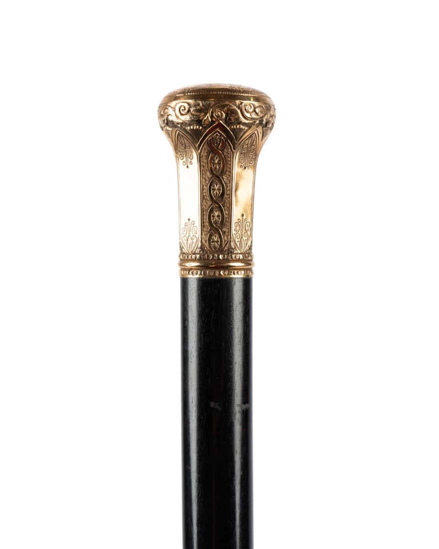 AMERICAN PRESENTATION CANE, 1882: American, 1882. Presentation cane with a gilt handle engraved with decorative motifs on each side, the top inscribed "Presented to Edward Walsh by the OLPN, April 7, 1882", ebony wood shaft terminatin