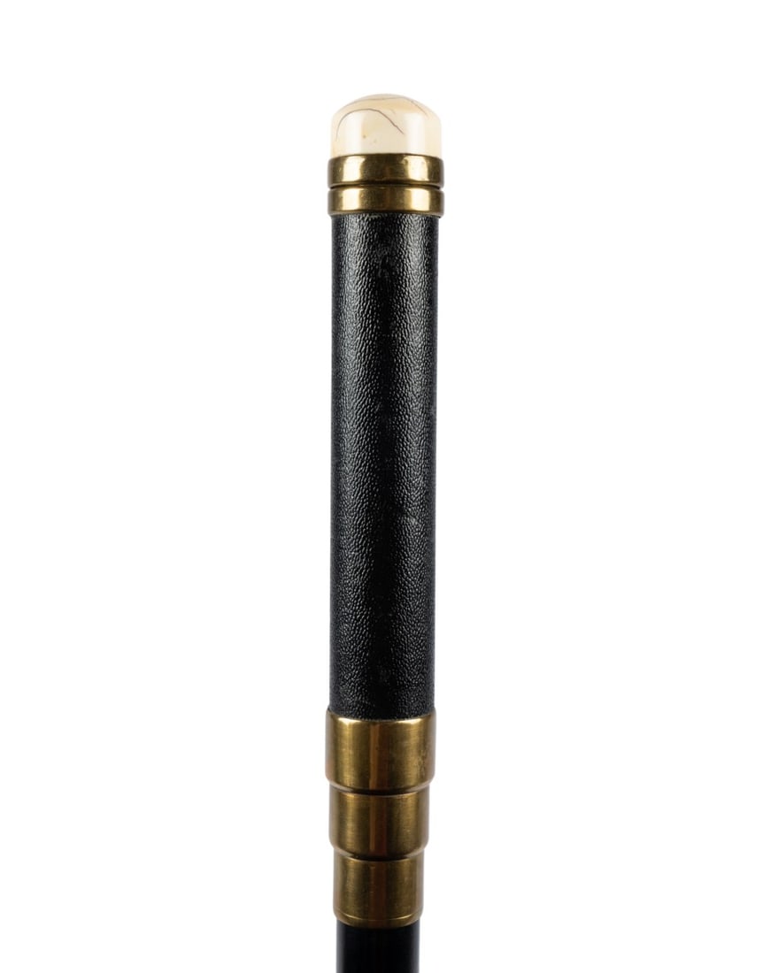 19TH C. ENGLISH SOVEREIGN ROCKER SCALE CANE: English, circa 1890. Walking cane with a turned knob handle attached to brass, with a leather grip supported by three brass rings, with a shaft of ebonized hardwood terminating at a large horn