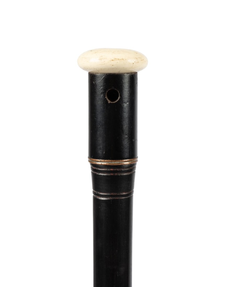 FRENCH 1913 EXPOSITION UNIVERSELLE CIGARETTE CANE: French, 1913. Souvenir cane of the Exposition Universelle de Gand with a white porcelain handle that unscrews to reveal a cigarette holder of ebonized wood, with a painted wood shaft terminating at a