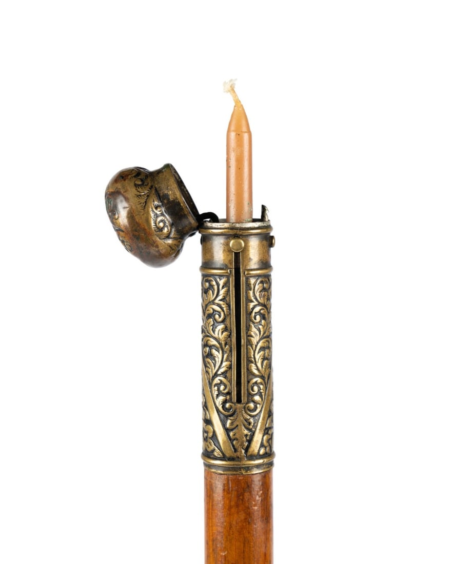 19TH C. CANDLE AND MATCH SAFE GADGET CANE: Continental, circa 1887. Gadget walking cane with brass knob handle opening with push button mechanism, side compartment for thin taper candle and matches, honey-toned cedar wood shaft with brass ferr