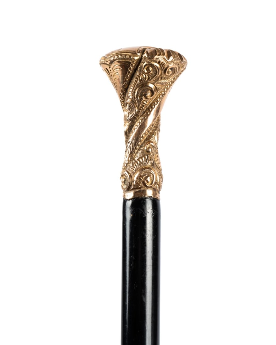 19TH C. AMERICAN GILT HANDLED DRESS CANE: American, circa 1890. Walking cane with ornate gilt handle with twist pattern along its length and detailed monogram engraved at the top, with ebonized hardwood shaft terminating in a metal ferrule. A