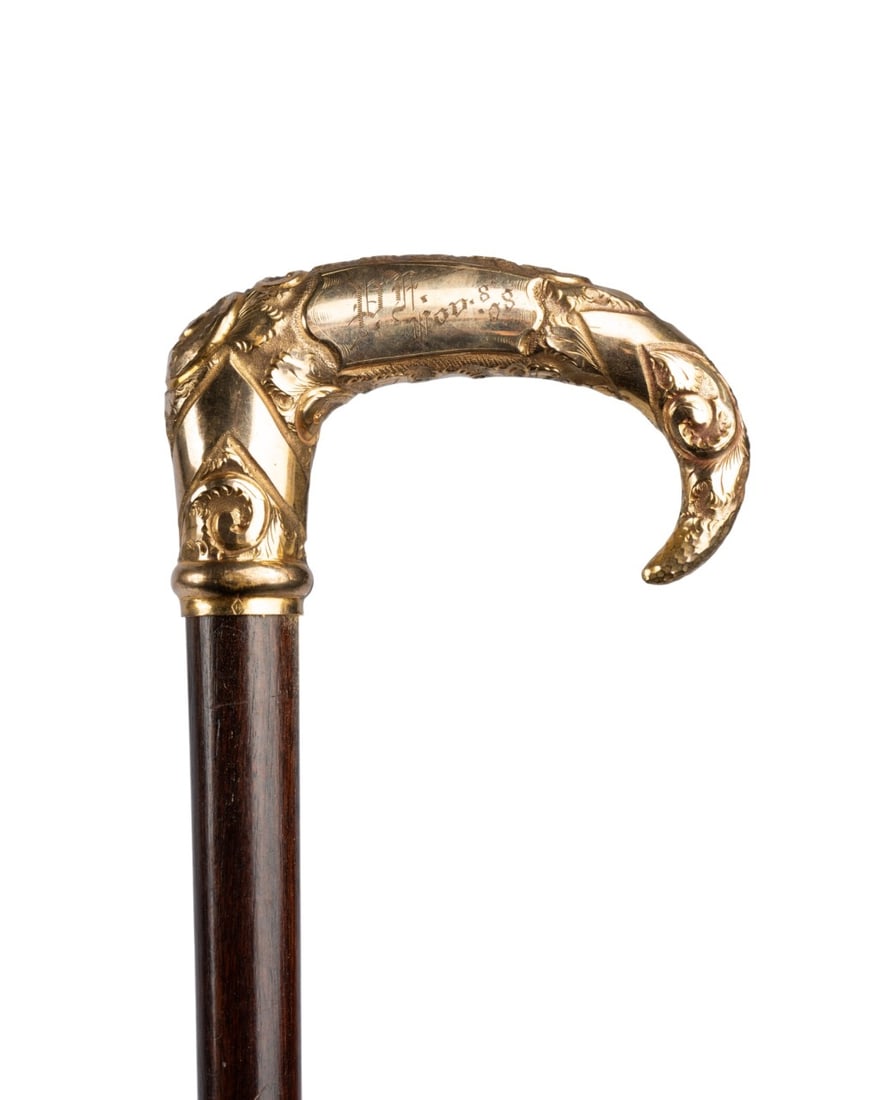 AMERICAN PRESENTATION DRESS CANE, 1908: American, 1908. Walking cane with elaborate gilt shallow hook handle with a mixture of engravings and relief at the sides, cartouche on one side engraved "P.F. Nov. 8, 08," with finely stained hardwoo
