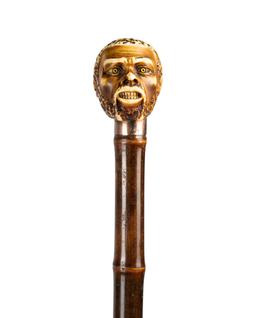 19TH C. CARVED BUST OF AFRICAN MAN WALKING CANE: English, circa 1880. Walking cane with carved bust of African man handle with glass eyes and detailed staining, supported by gilt collar, with bamboo shaft terminating in brass ferrule. Approximate me