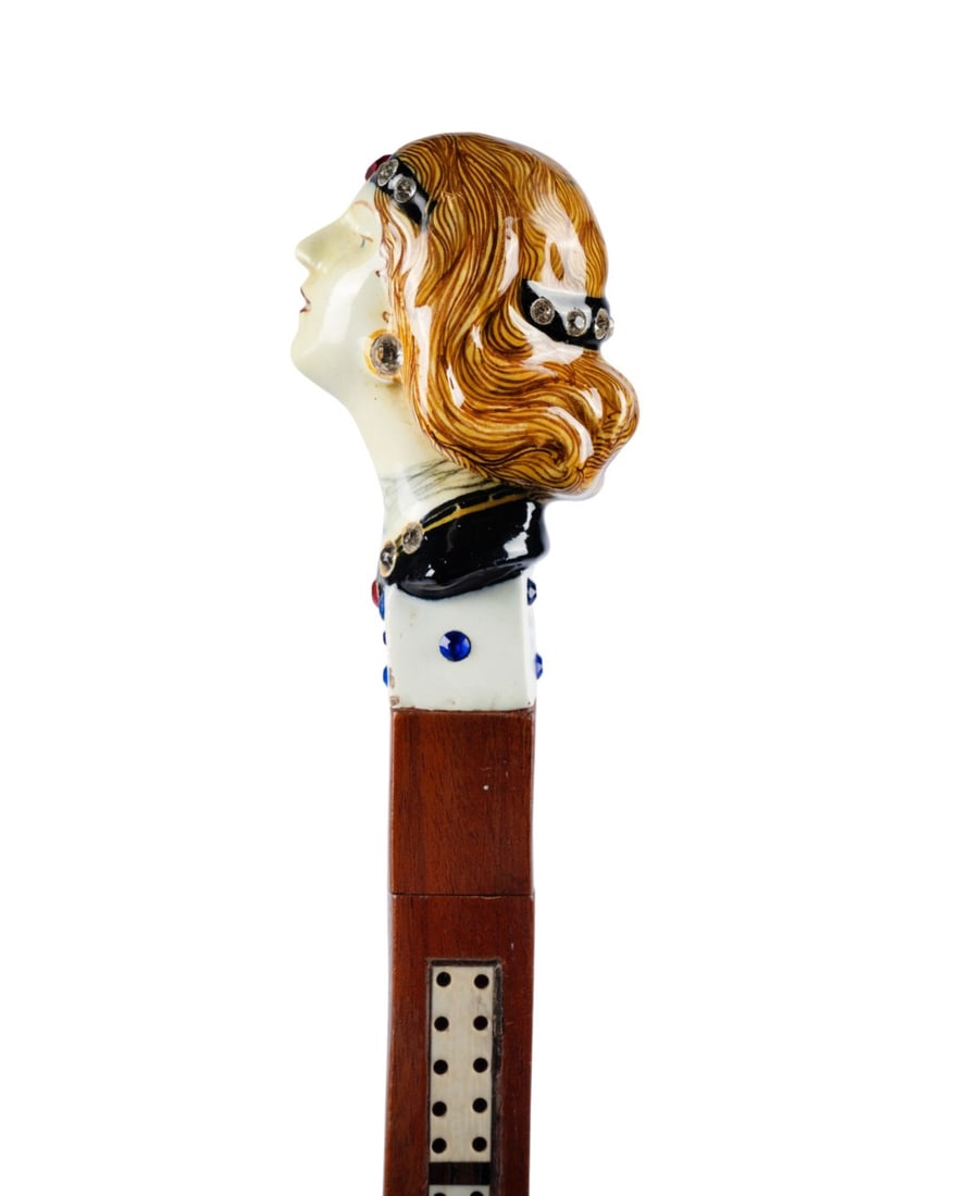 ITALIAN MAJOLICA FLAPPER HANDLE GADGET CANE: Italian, circa 1920. Art Deco walking cane with Italian majolica handle of flapper bust with glass jewels, mounted on single dice with blue glass dots, marked "Salvini, Italy, Brevete" at back; square
