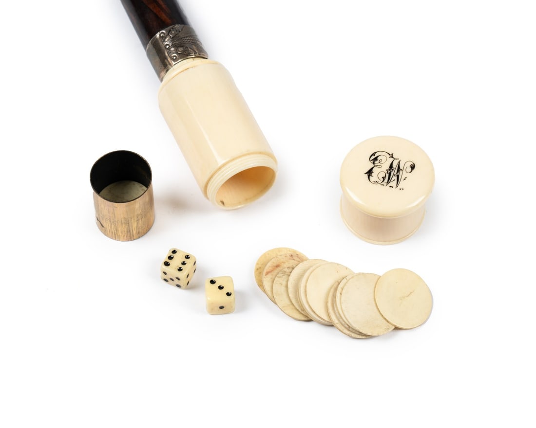 19TH C. ENGLISH GAMBLER'S CANE: English, circa 1890. Gambler’s walking cane with carved bone handle inscribed with monogram "E. W.", dark-stained fruitwood shaft with copper ferrule, containing a pair of carved dice and 15 carved