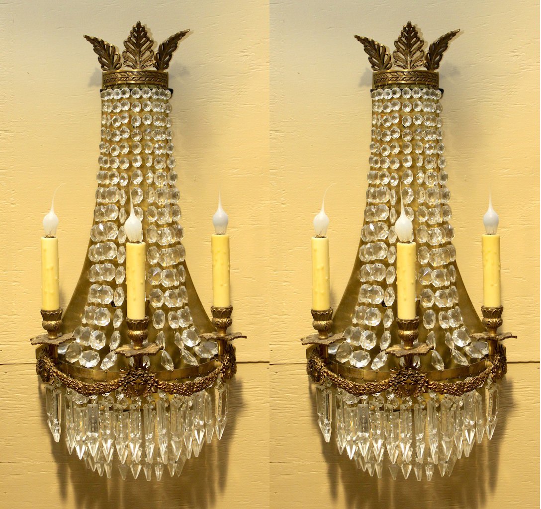 Pair of Regency Brass Wall Sconces: Crystal prisms and Egyptian face with bronze garland wreath detail. Removed from a Swedish Movie House and imported by Georgia Lighting in the mid 1980's. Measures 26" tall and 12 1/4" wide.