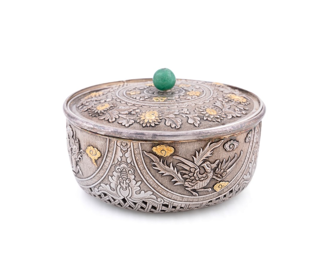 CHINESE EXPORT SILVER AND GILT CRICKET BOX: Chinese, late 19th / early 20th century. Round silver cricket box having embossed designs depicting dragons and another mythological animal with pierced lattice base, lid with embossed flower and leaf