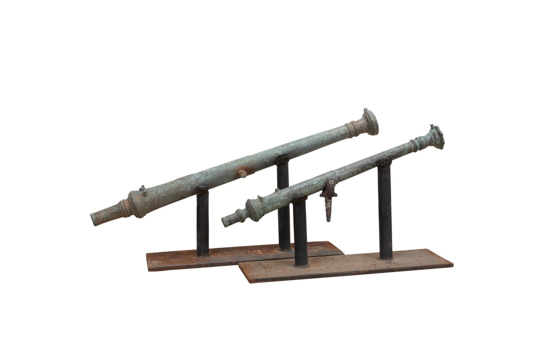 PAIR OF ANTIQUE BRONZE ASIAN LANTAKA CANNONS: Indonesia,18th-19th century. Two bronze Lantaka cannons with original patina. smaller is fitted with a swivel, apparently unmarked. Accompanied by stands. Provenance: The Estate of Edward and Mary