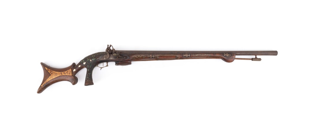 19THC.OTTOMAN SILVER INLAID CARVED FLINTLOCK RIFLE: Ottoman Empire, 19th century. Large heavy-barreled flintlock rifle, having heavily carved and richly ornamented silver and mother-of-pearl inlay; includes its wooden ramrod. Shield with Arabic