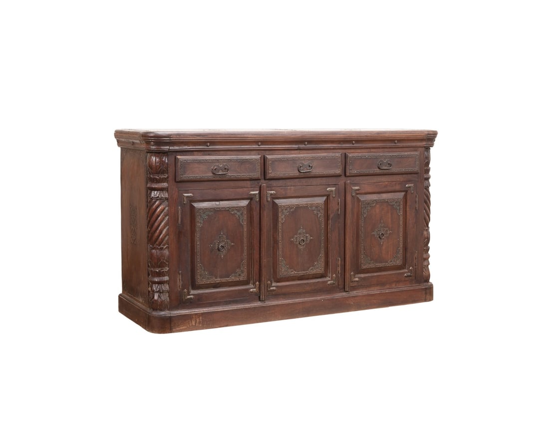 MOORISH STYLE DARK STAINED WOOD CABINET BUFFET: Moorish style dark stained wood buffet, having chased metal trim with nailhead accents, carved column form corners, and raised on a plinth base, apparently unmarked. Provenance: The Estate of Edward a