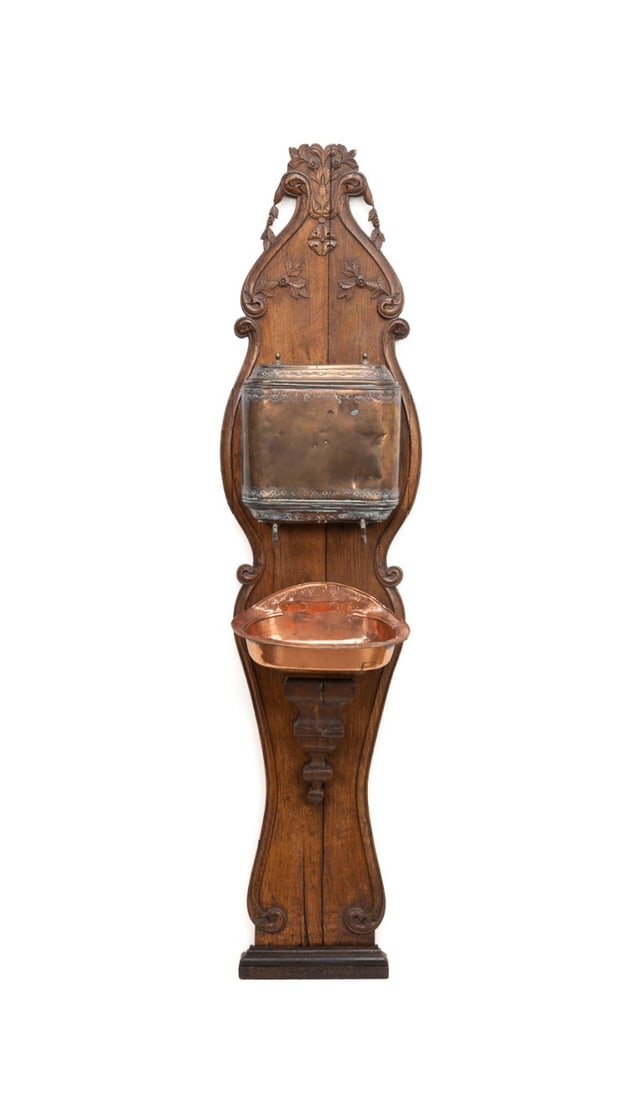 19TH C. CONTINENTAL WALNUT & COPPER LAVABO: Continental, 19th century. Wall mounted lavabo, having a copper reservoir and basin on a shaped foliate carved oak backboard, the reservoir stamped "66" over "M". Provenance: Estate of Scott Hudgens a