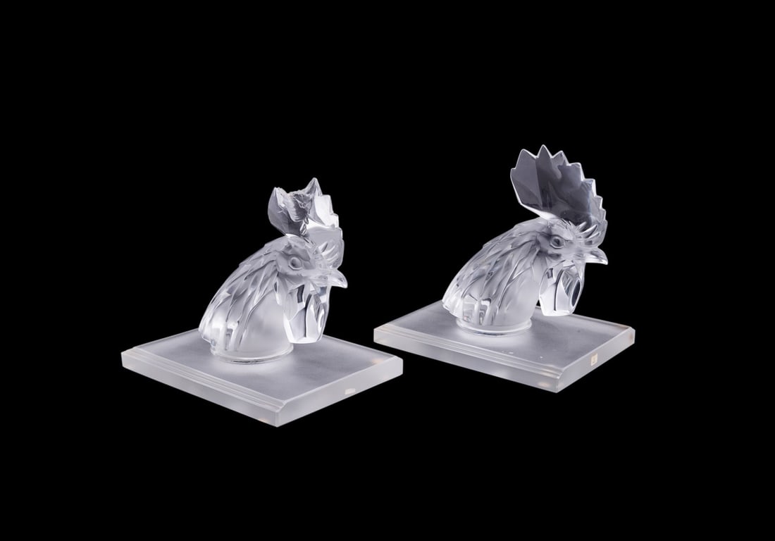 LALIQUE, PAIR OF 'TETE DE COQ' ROOSTER BOOKENDS: Lalique (French, founded 1888), 20th century. Pair of colorless partial frosted crystal rooster head bookends, each modeled after the "Tete de Coq" automobile mascot, model number 1137, both appropria
