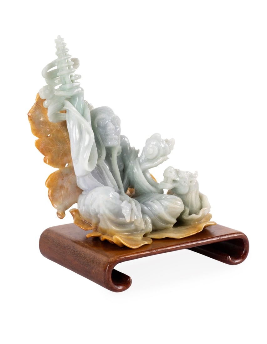 CARVED JADEITE FIGURE OF A WISE MAN WITH DRAGON: Asian, 20th century. Pale green jadeite figure of a wise man holding a pagoda in his right hand and a conch shell in his left hand, a dragon emerging from a conch shell at this side, seated on yellow