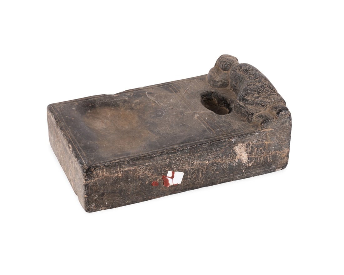 CHINESE INKSTONE WITH RECLINING FIGURE RELIEF: Chinese, 19th century. Carved inkstone with well and grinding surface, a reclining figure carved in relief on the end, and incised floral design on the sides, apparently unmarked. Approximate dimensio