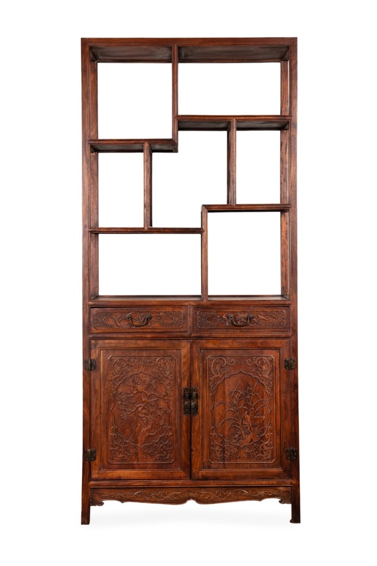 CHINESE ROSEWOOD DISPLAY CABINET: Chinese, 20th century. Rosewood cabinet with asymmetrical open bookcase having intricately carved doors and drawers, carved apron, raised on stile feet, apparently unmarked. Approximate dimensions: