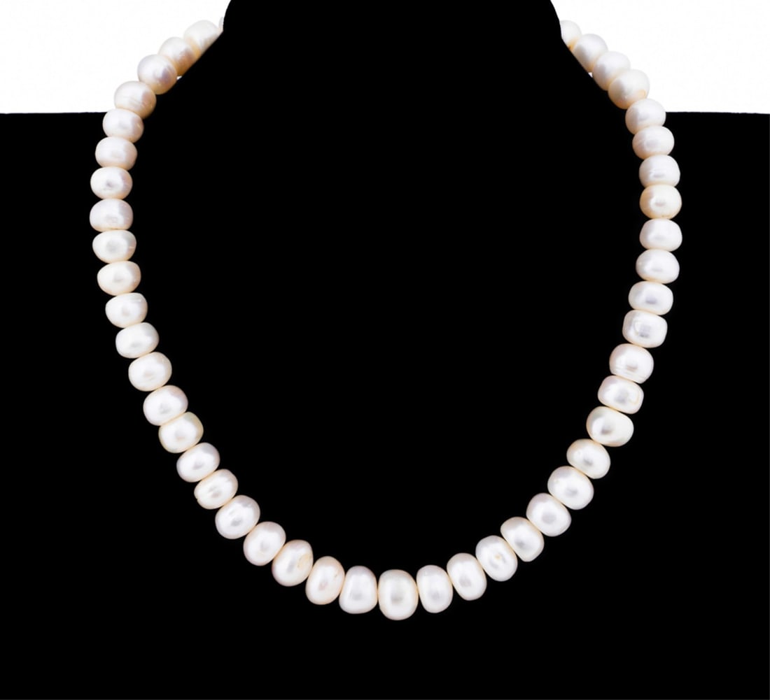 CULTURED FRESHWATER PEARL NECKLACE: Cultured freshwater pearl necklace featuring cultured freshwater button pearls measuring from approximately 10.0 - 11.5mm with sterling silver clasp. Marked appropriately. Provenance: The Estate of