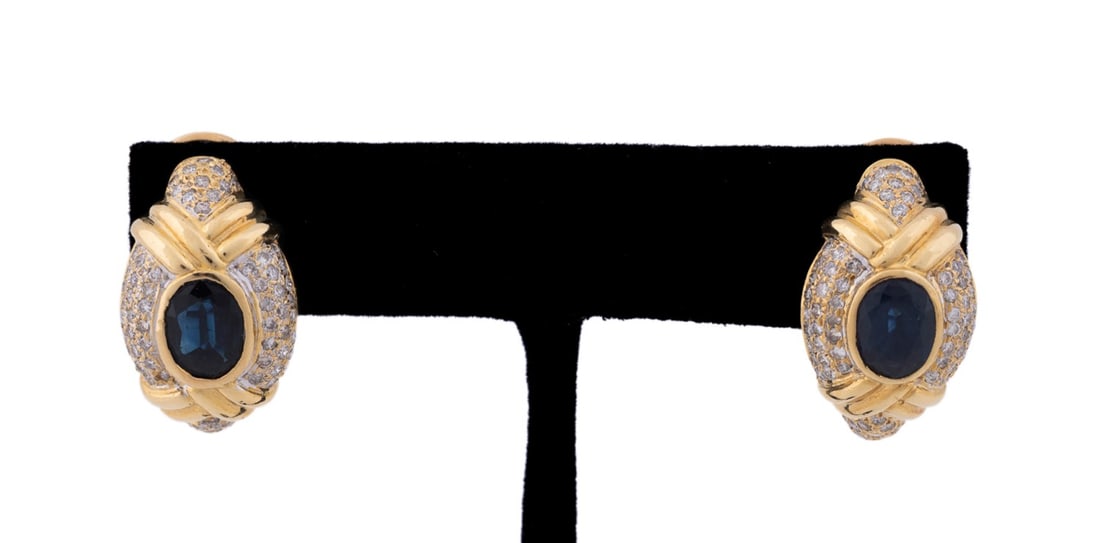 BLUE SAPPHIRE AND DIAMOND EARRINGS, SET IN 18K YG: Pair of sapphire and diamond earrings featuring (2) oval shape dark blue sapphires weighing approximately 2.60 total carats surrounded by (14) round brilliant cut diamonds weighing approximately 1.50