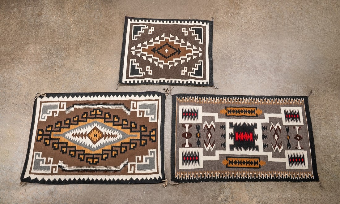 THREE HANDWOVEN NAVAJO RUGS, TWO GREY HILLS/STORM: Native American, late 20th century. Group of three handwoven Navajo rugs comprised of one Two Grey Hills rug having an ochre, white, grey, brown, and black design, one Storm Pattern rug having a white