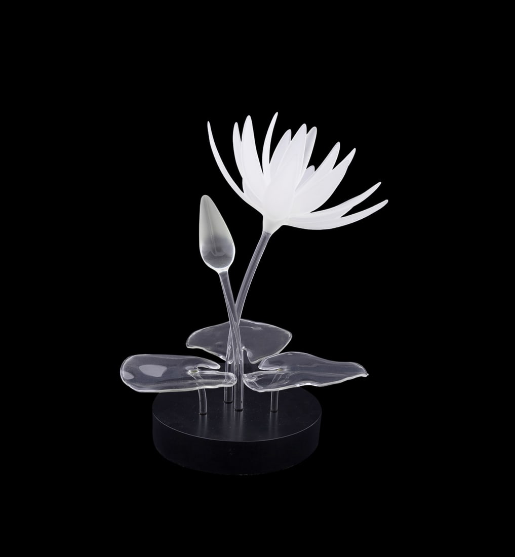Hans Frabel, Lotus Flower, 1999, Blown Glass: Hans Godo Frabel German, born 1941 Lotus Flower - 1999 Blown glass on a black base Colorless and frosted flower, bud, and leafs, etched "FS" (Frabel Studio) and dated to leaf. Overall: 15 1/4 x 12 x